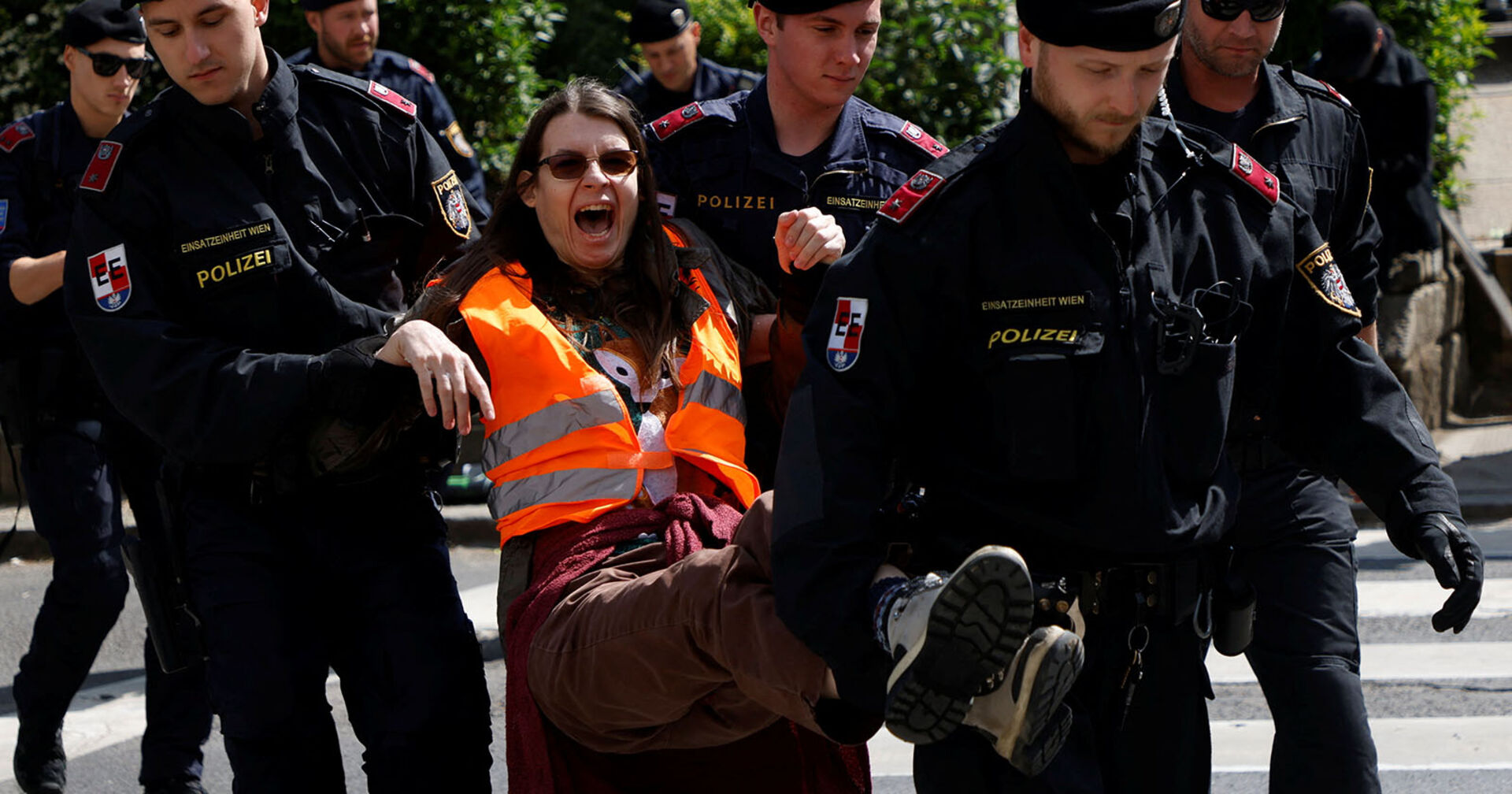 Eine Aktivistin der &quot;Letzten Generation&quot; wird von Polizeibeamten von der Fahrbahn getragen