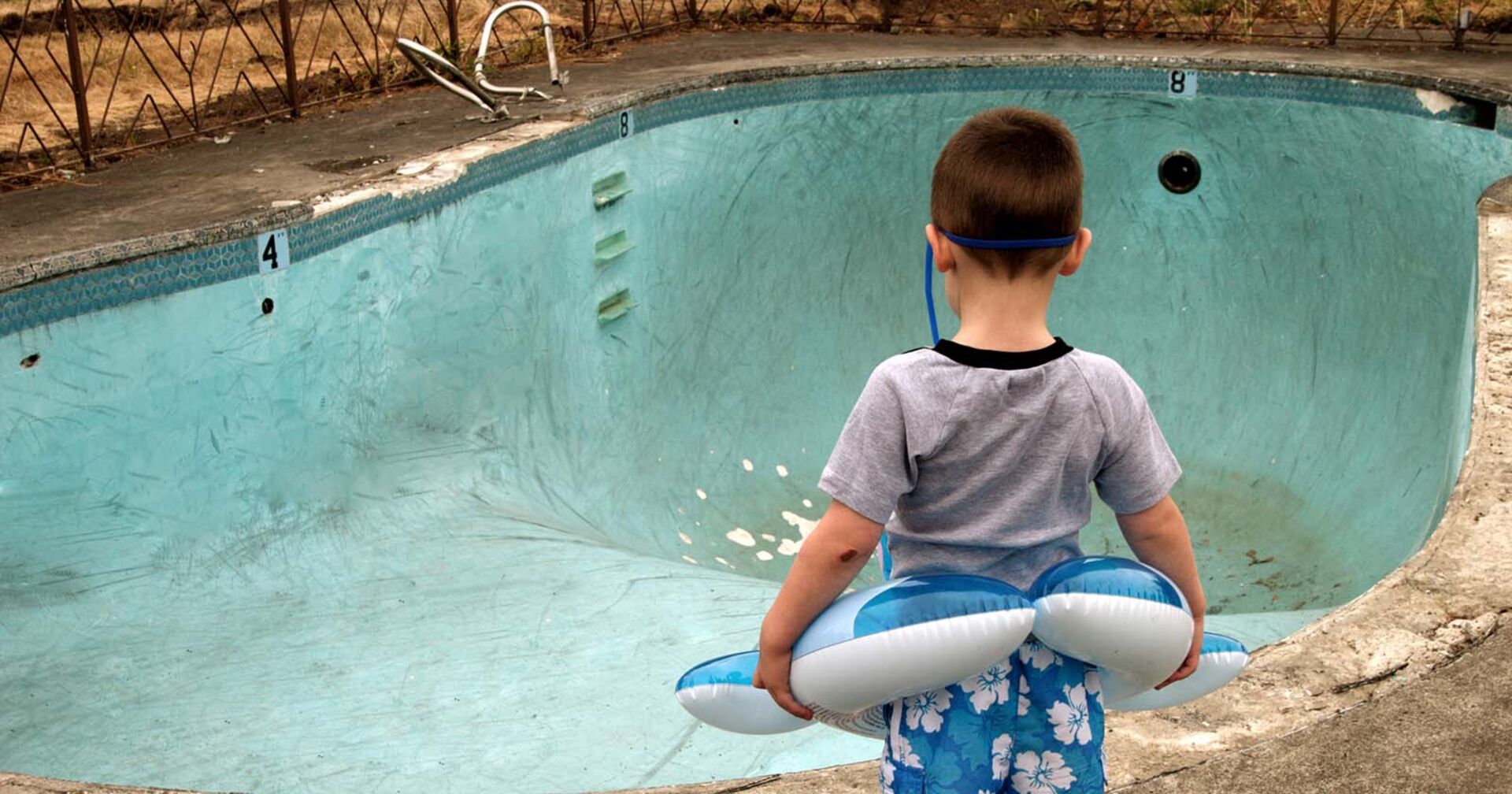 Kind steht vor leerem Schwimmbecken