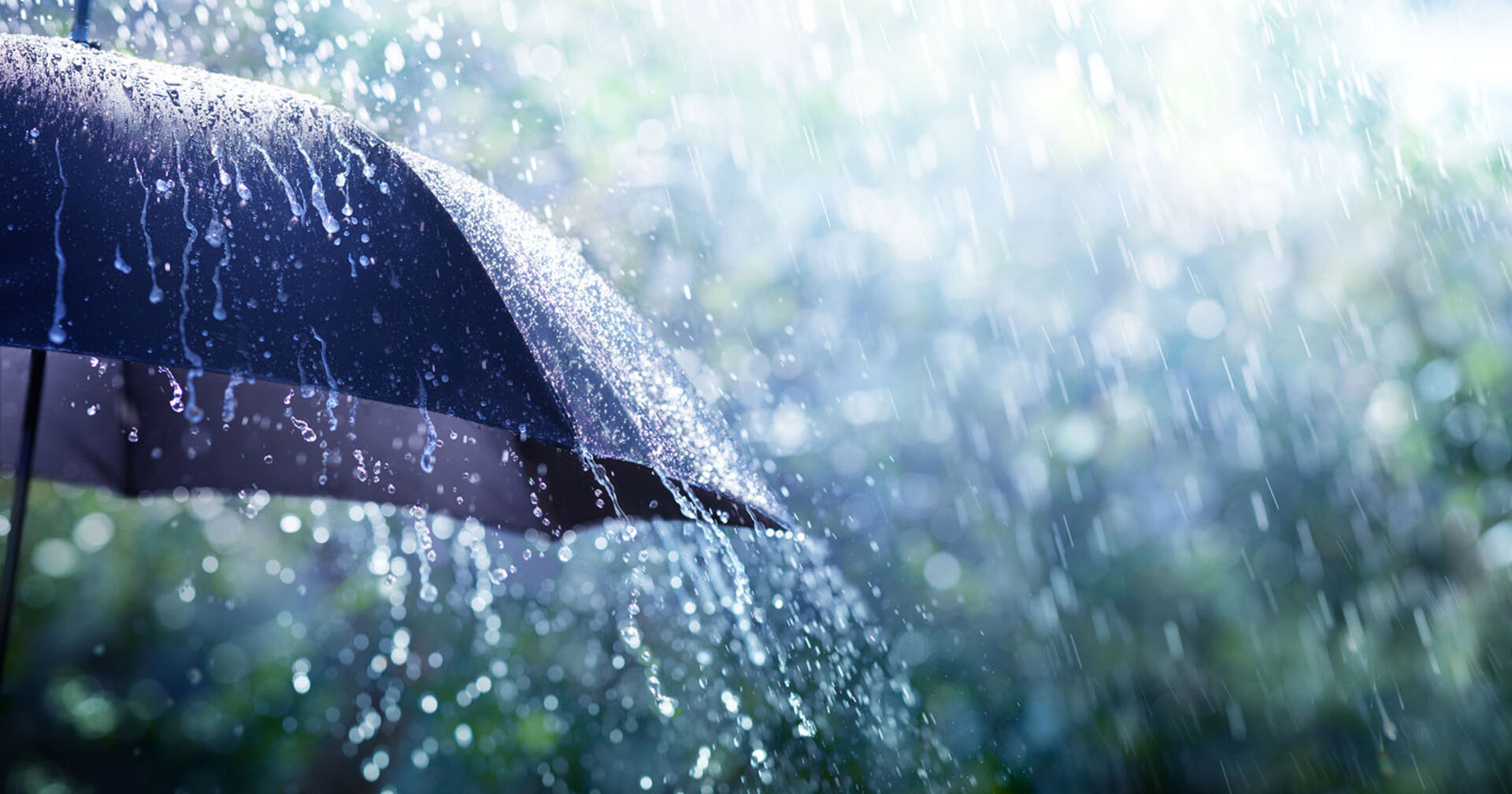Starker Regen tropft von einem Schirm ab