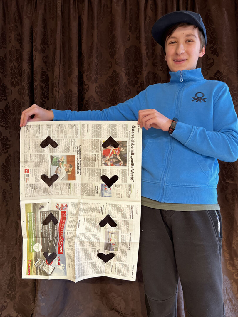 Nico führt einen Trick mit Zeitungen vor.