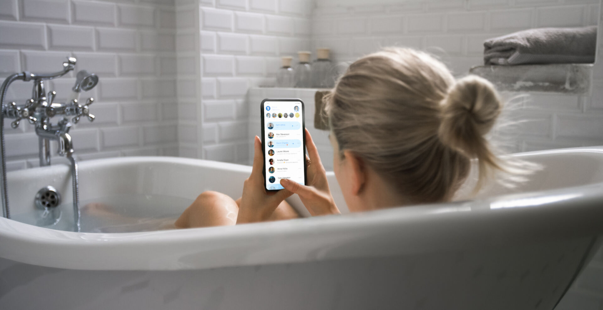 Frau liegt mit Handy in der Badewanne