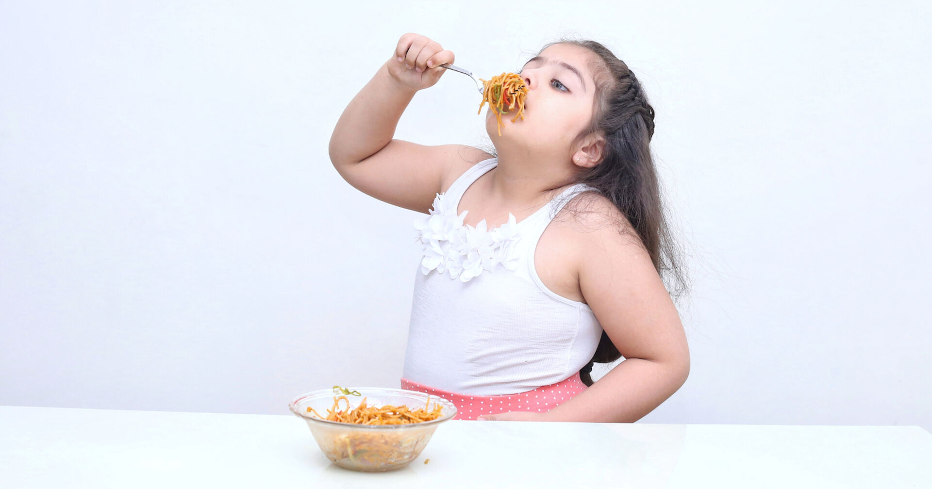 Ein übergewichtiges Kind isst Spaghetti.