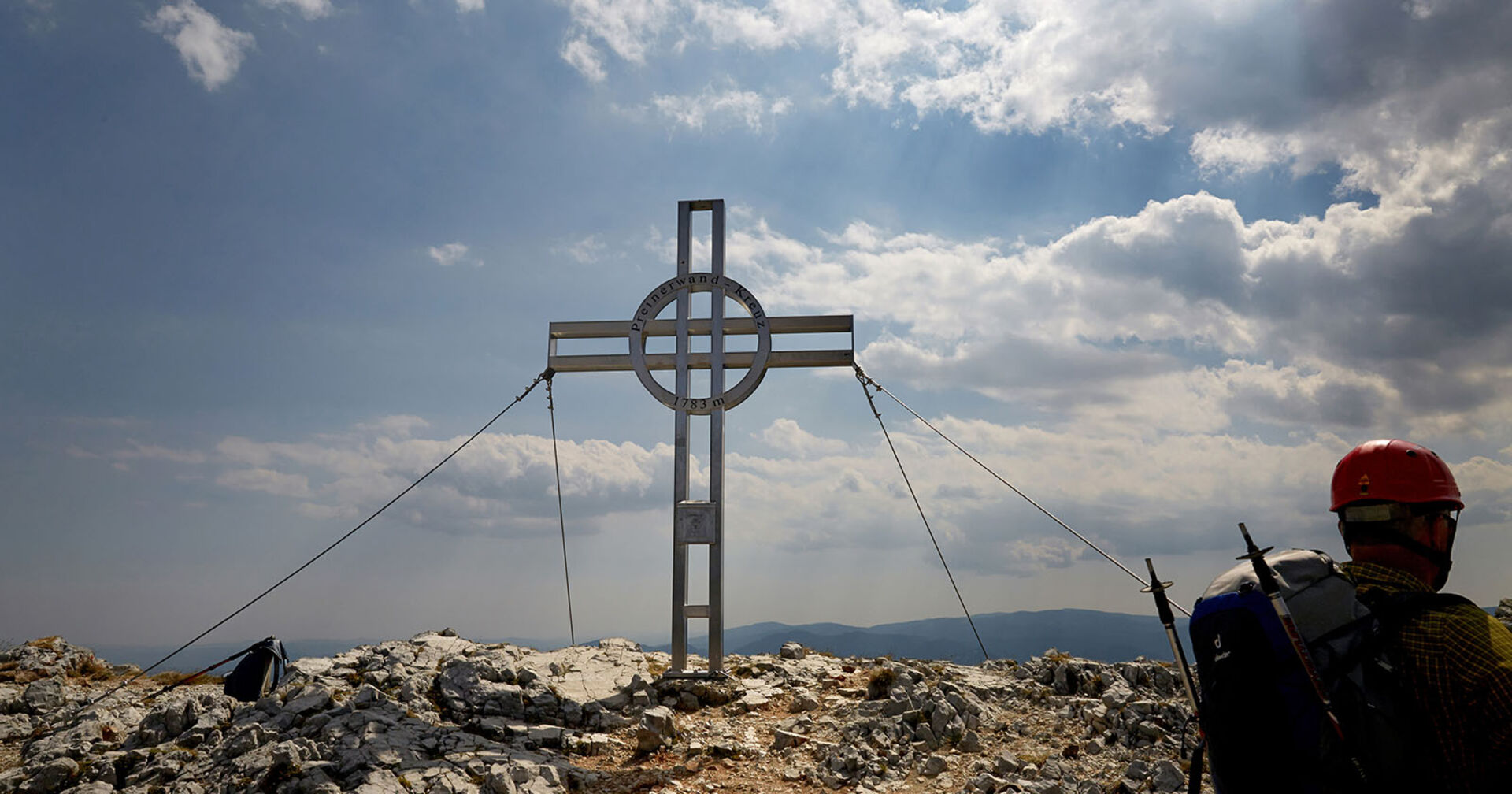 Kletterer steht am Gipfelkreuz | Credit: Hans Ringhofer / picturedesk.com