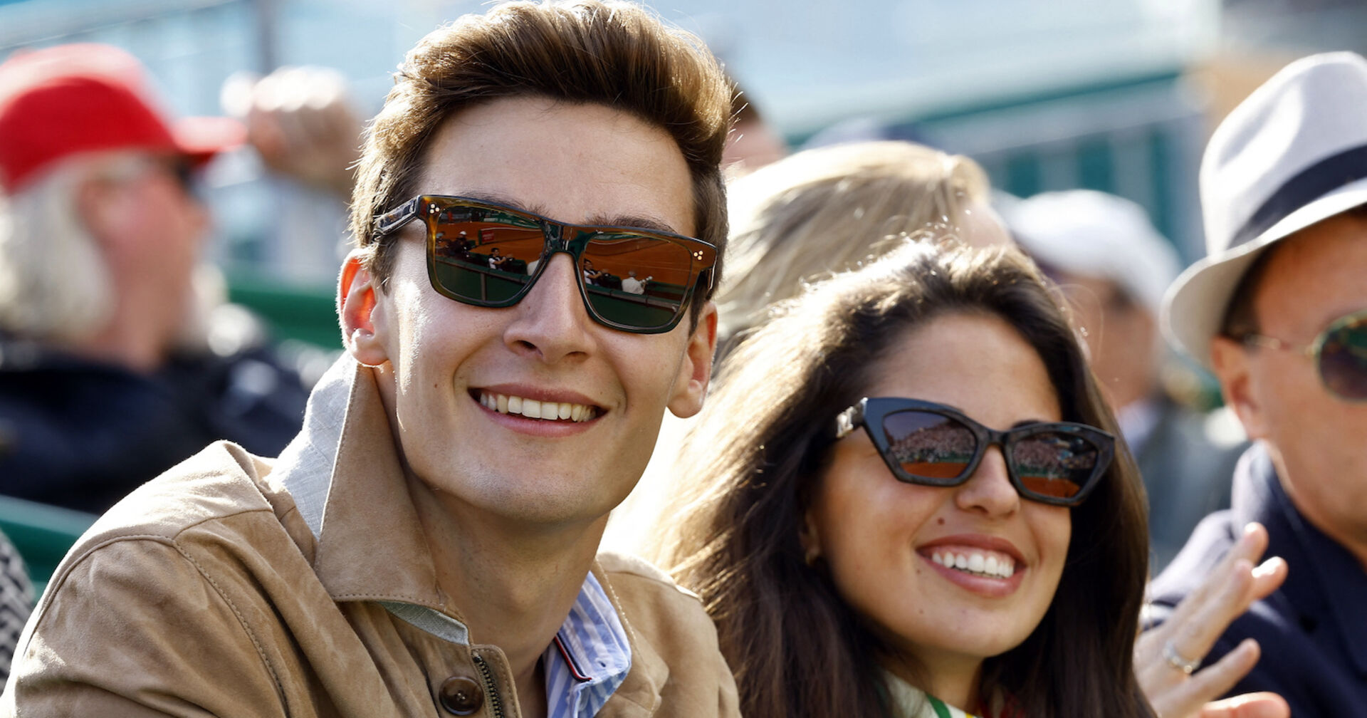 Russel neben Freundin Carmen Montero Mundt sitzend. Beide tragen Sonnebrillen und lachen.