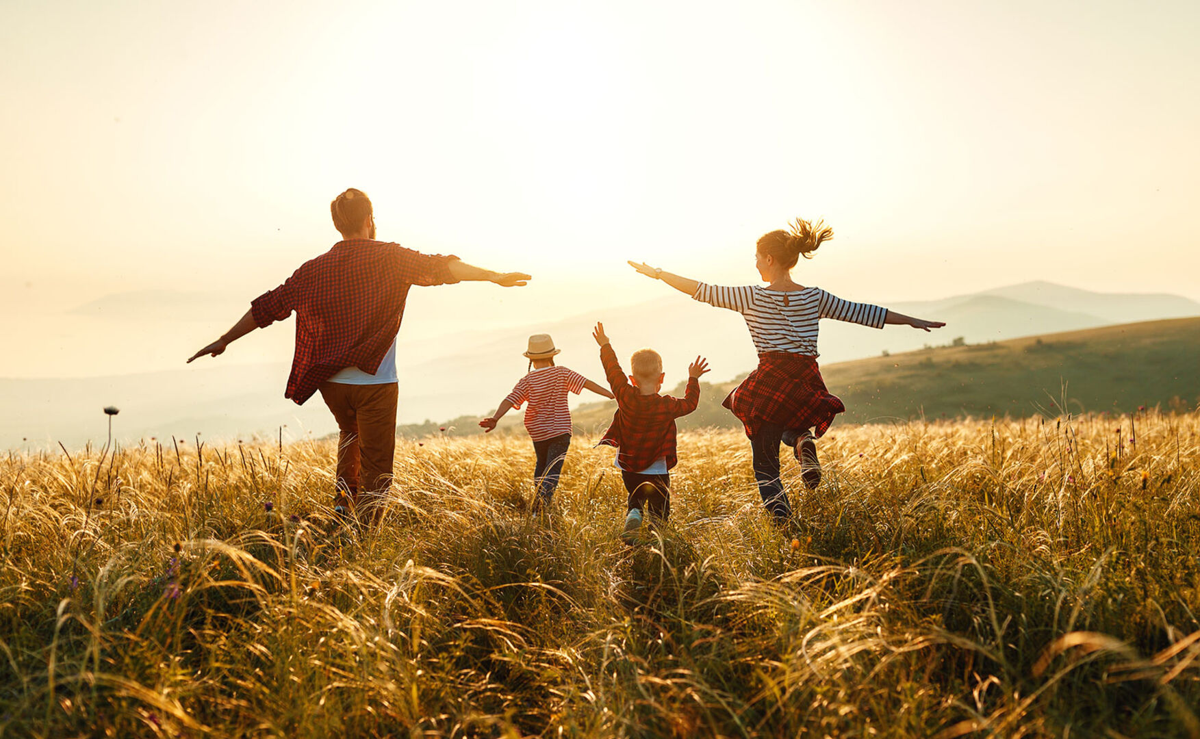 Mutter und Vater und mit Tochter und Sohn im Sonnenuntergang | Credit: iStock.com/evgenyatamanenko