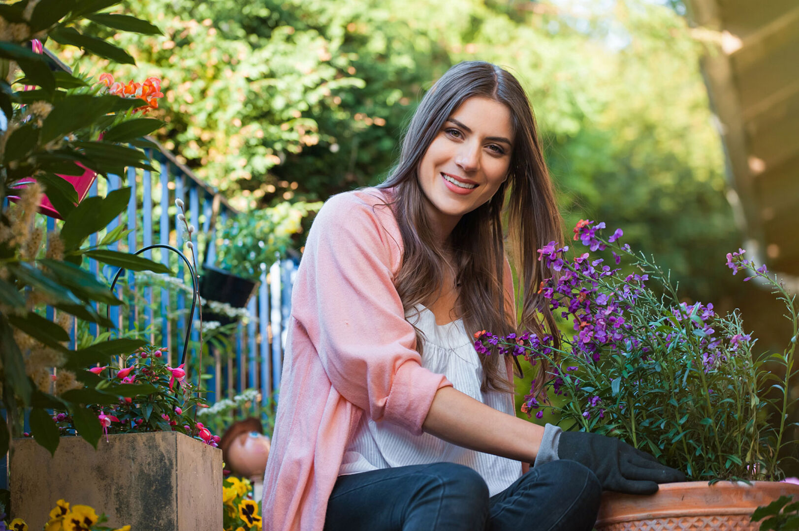Junge Frau pflanzt Blumen in ihrem Topf ein | Credit: iStock.com/VladTeodor