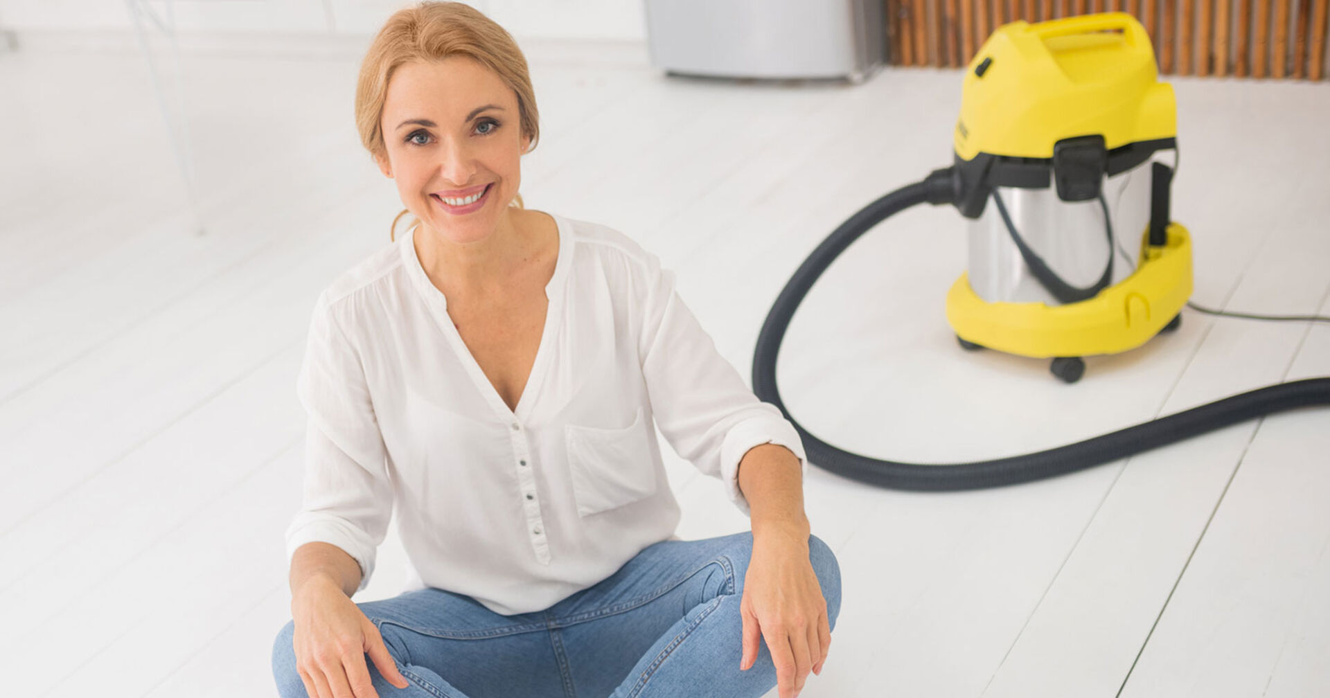 Junge Frau sitzt im Schneidersitz vor ihrem Nass-/Trockensauger | Credit: iStock.com/Zinkevych