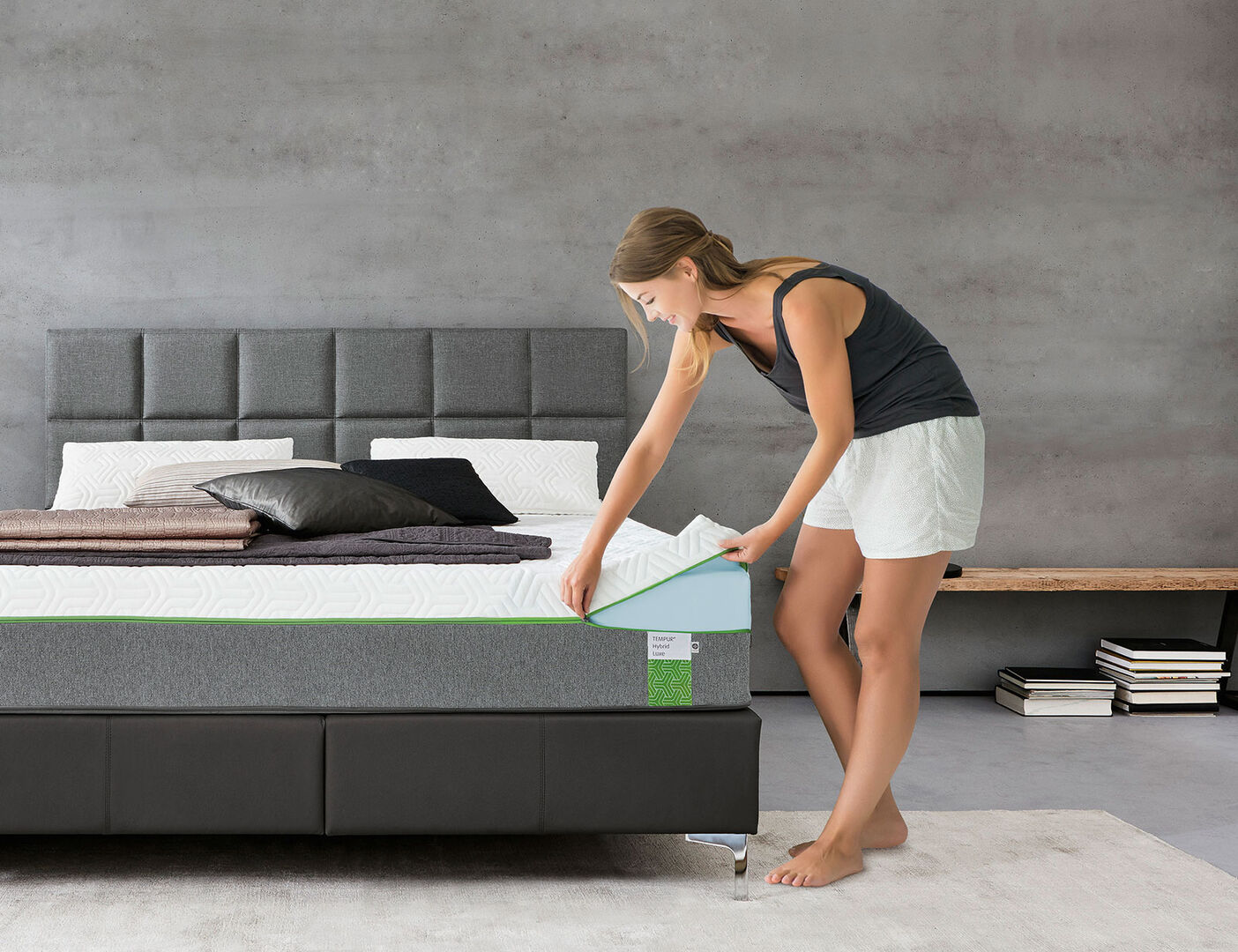 Junge Frau in Unterwäsche bezieht die Matratze ihres Bettes | Credit: XXXLutz