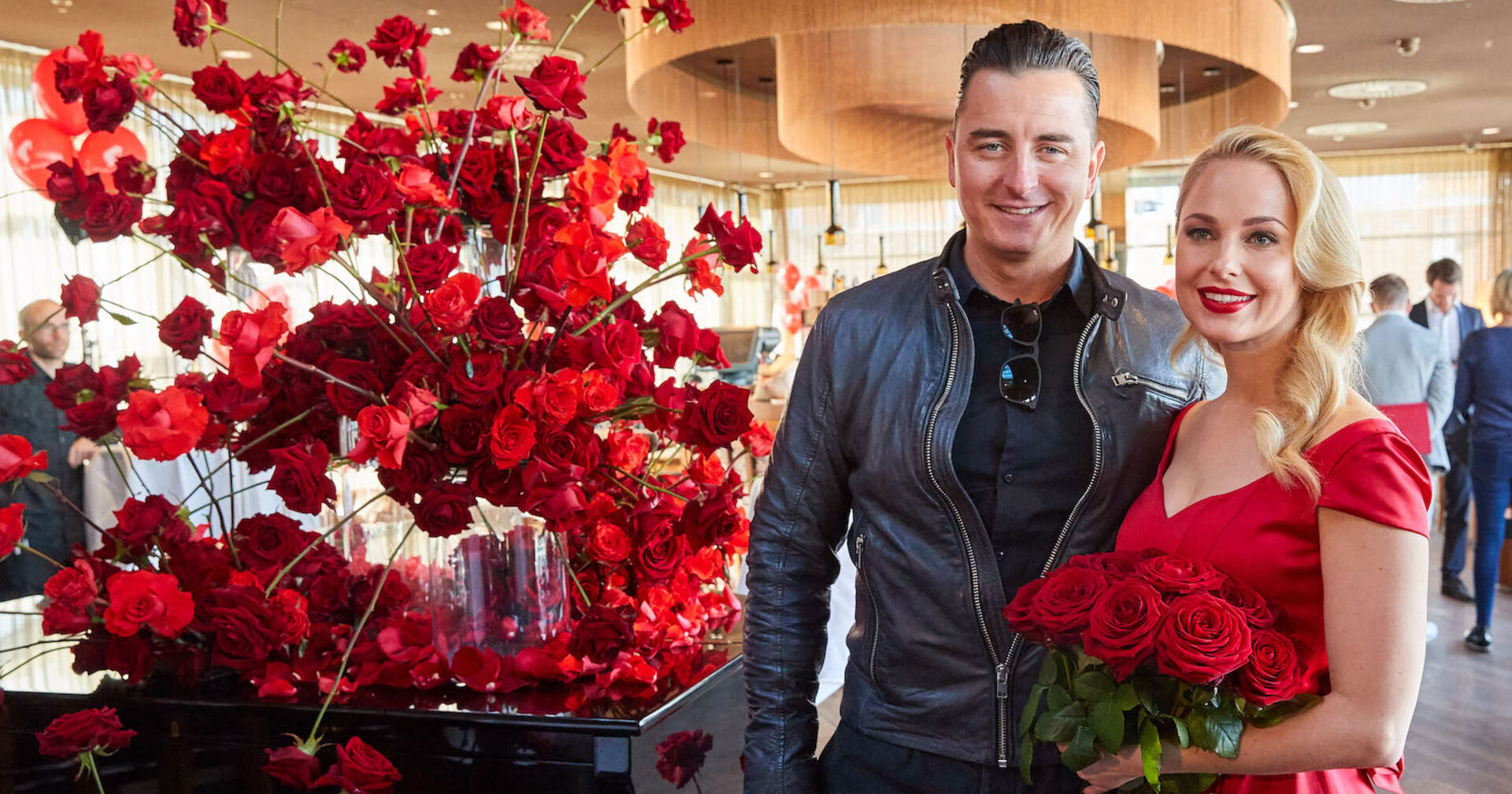 Silvia Schneider und Andreas Gabalier mit vielen Rosen im Hintergrund.