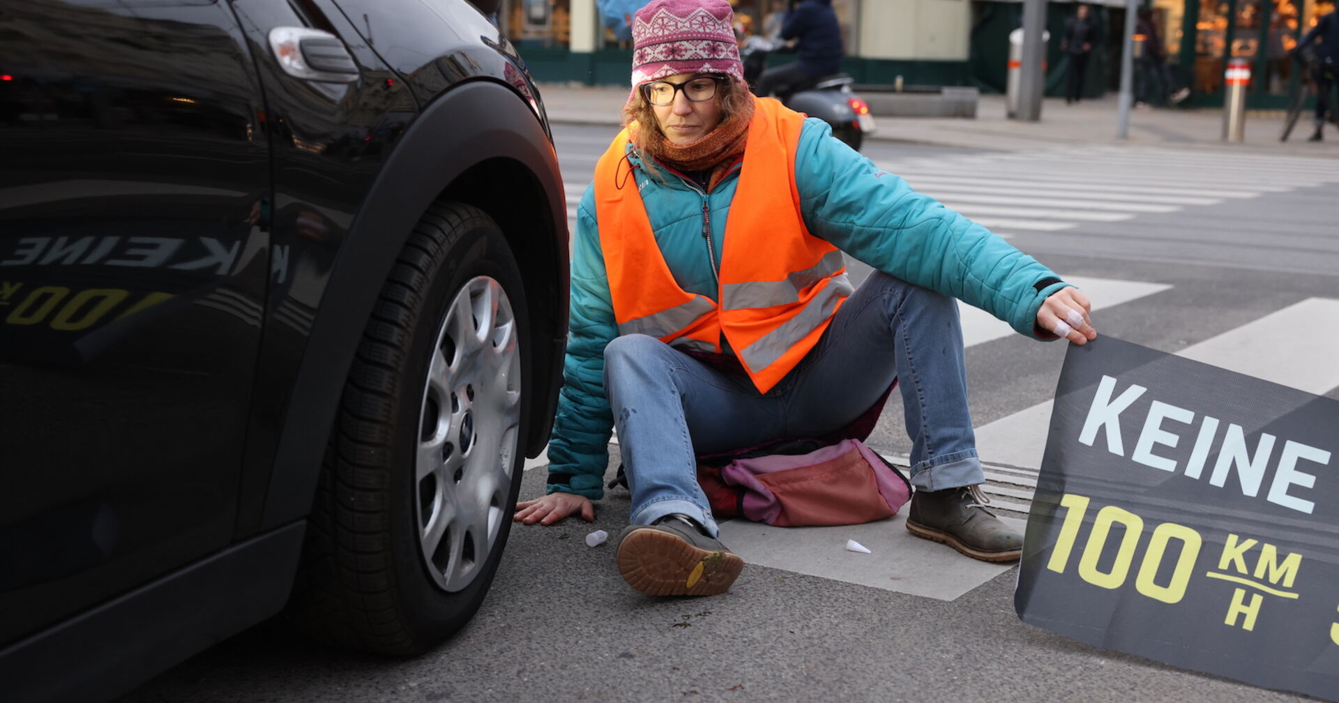 Eine Klima-Kleberin sitzt direkt vor einem Auto. (SYMBOLBILD)
