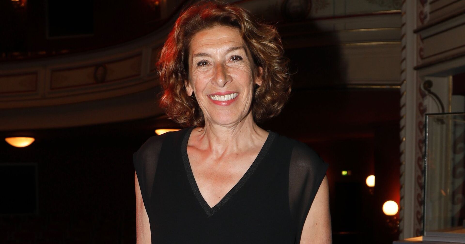 Adele Neuhauser vor schwarzem Hintergrund mit einem schwarzen Top