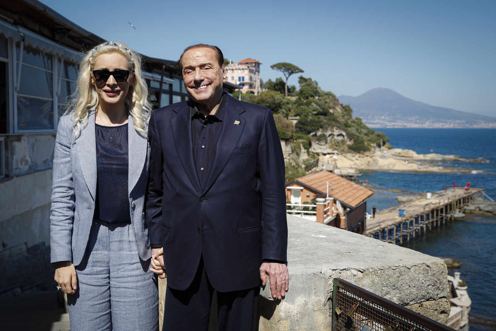 Ein alter Mann steht mit einer jungen Frau auf einer Terrasse mit Blick auf das Meer.