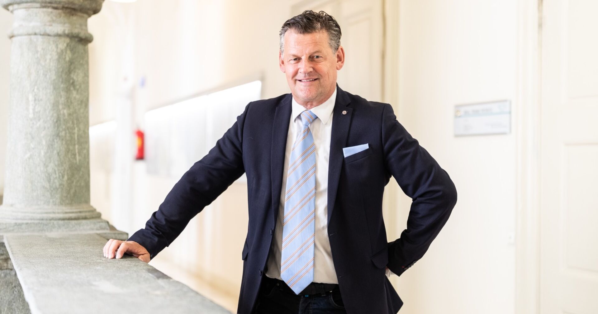 Bürgermeister Scheider, in Anzung und mit einer Krawatte, hinter einer Balustrade im Klagenfurter Rathaus