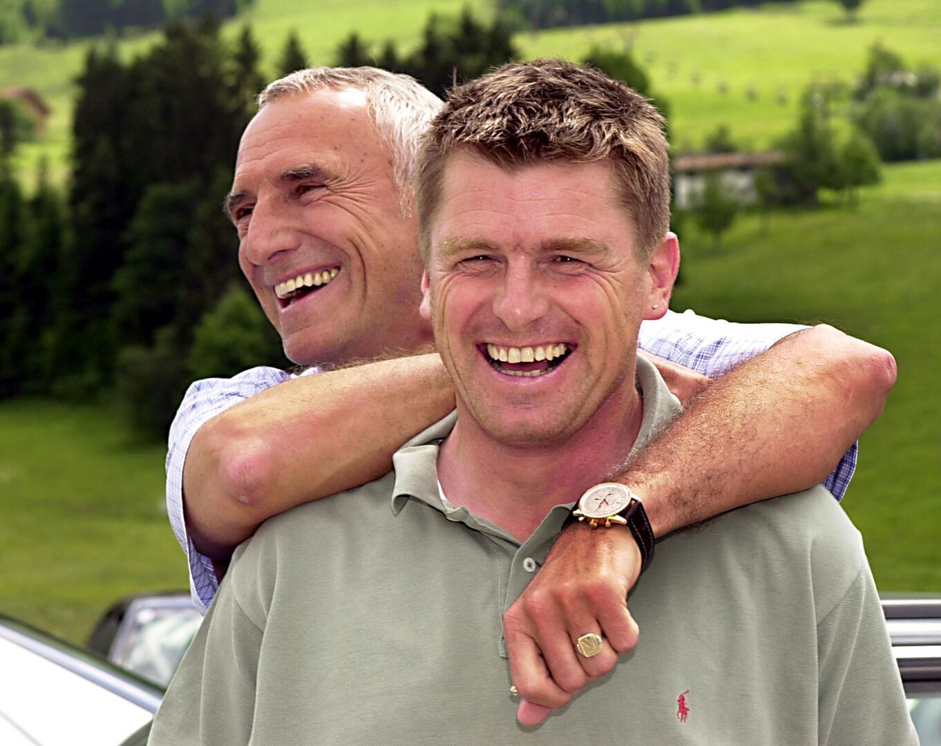 Zwei Männer lachen in die Kamera, der eine schaut seitlich vorbei