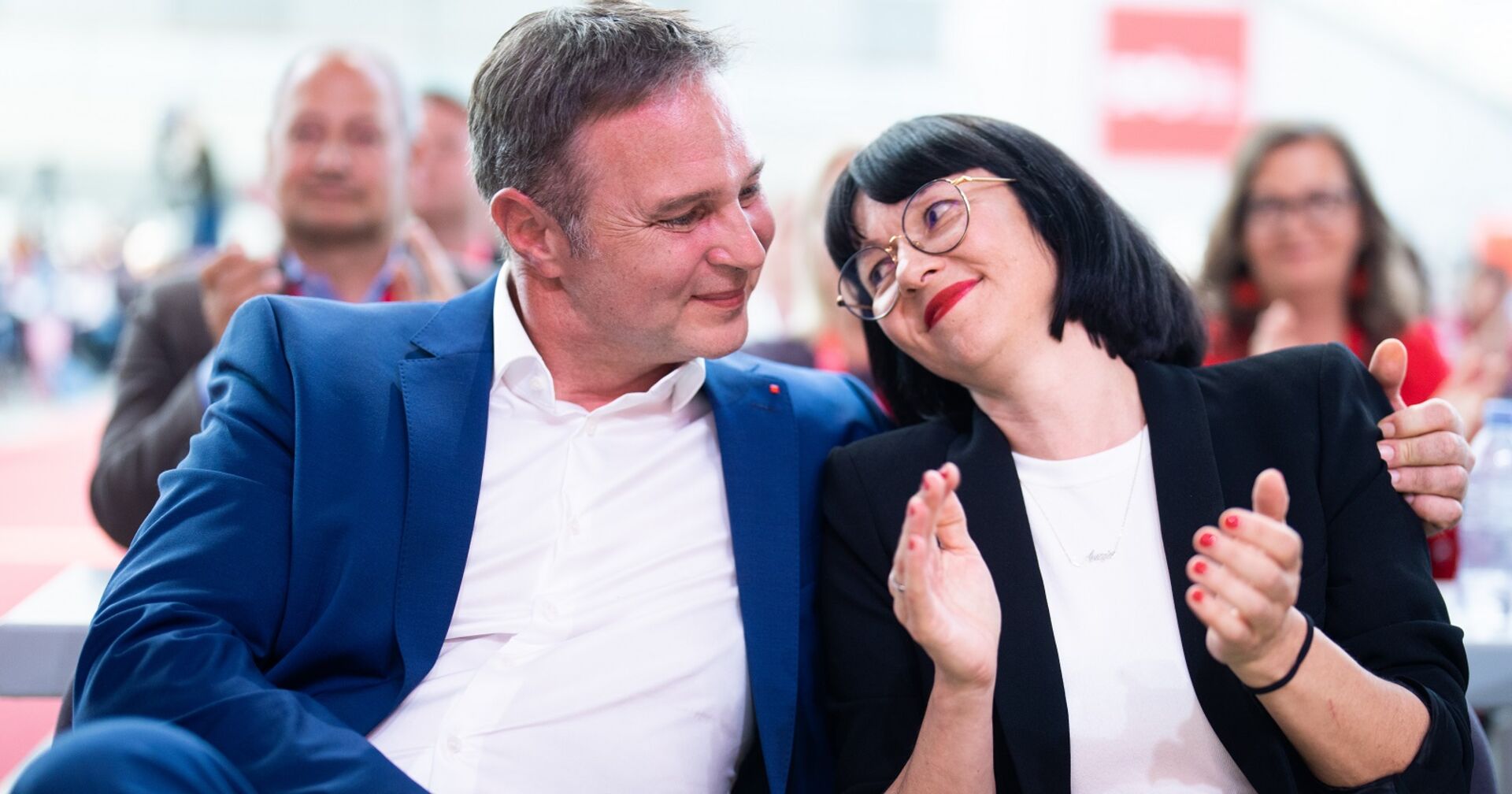 Babler sitzt neben seiner Lebensgefährtin und hat den Arm um sie. Die beiden schauen sich verliebt an.