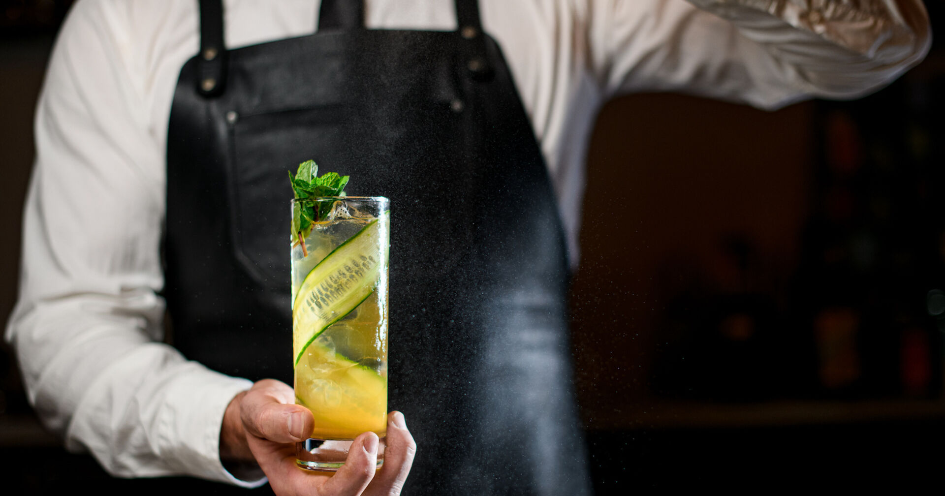 Barkeeper hält einen Cocktail mit einer langen Gurkenscheibe | Credit: istock.com/MaximFesenko