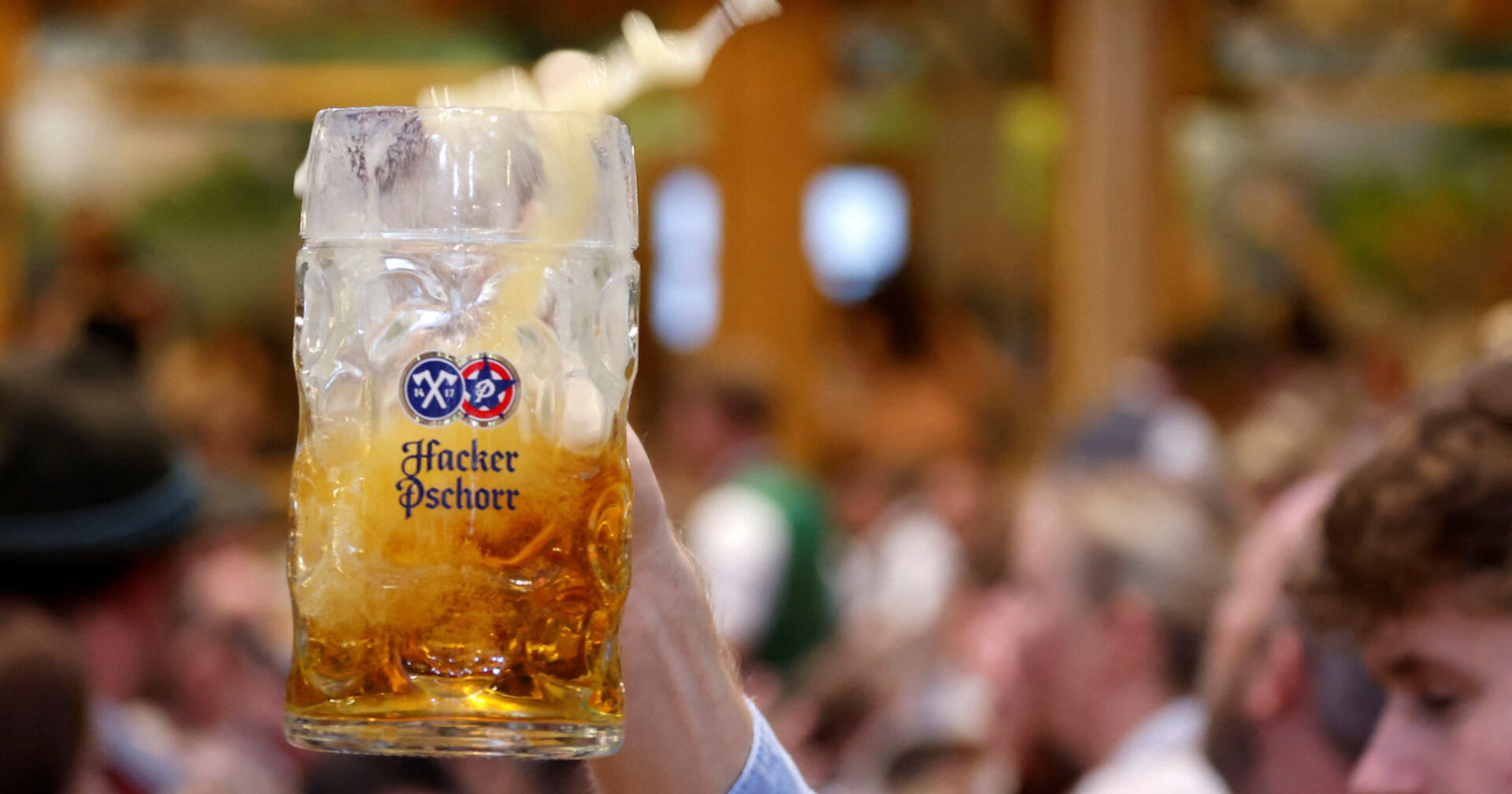 Jemand hält eine Maß Bier in einem Festzelt in die Höhe.