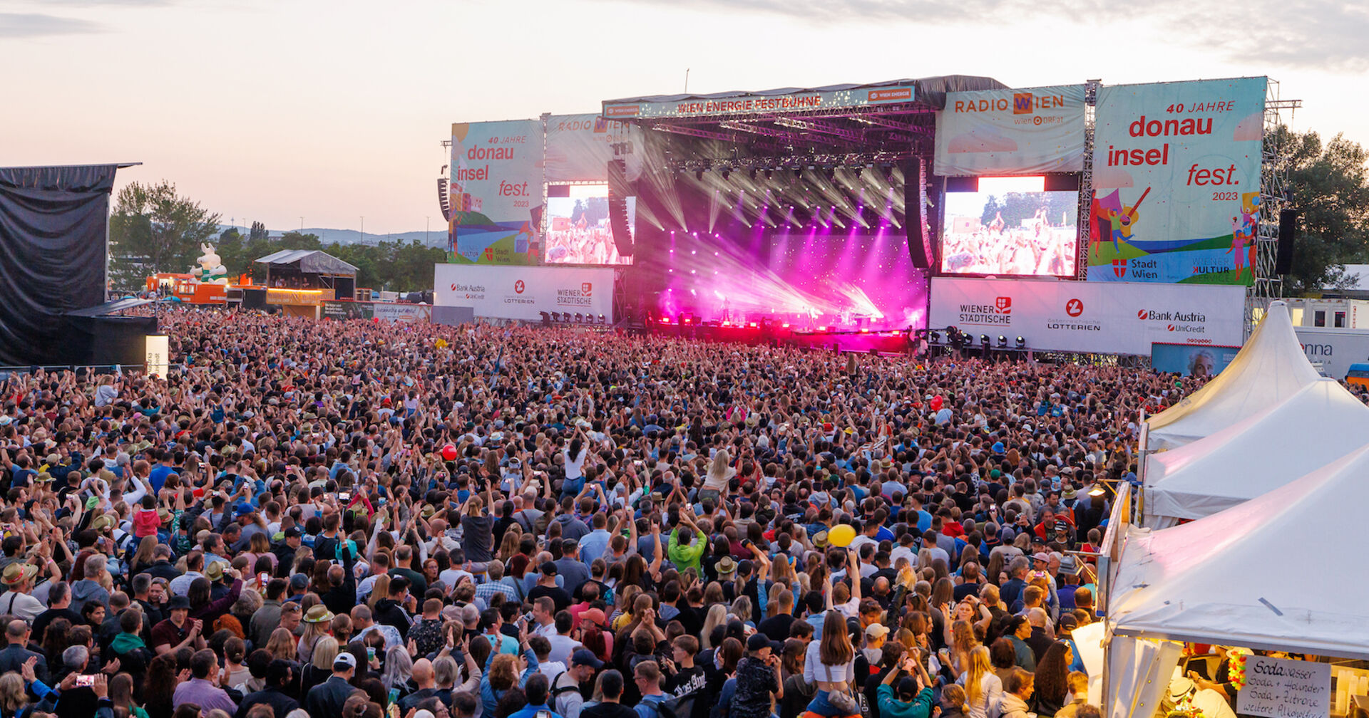 Eine große Menge Zuseher steht vor der Hauptbühne am Donauinselfest. Auf der Bühne eine Show