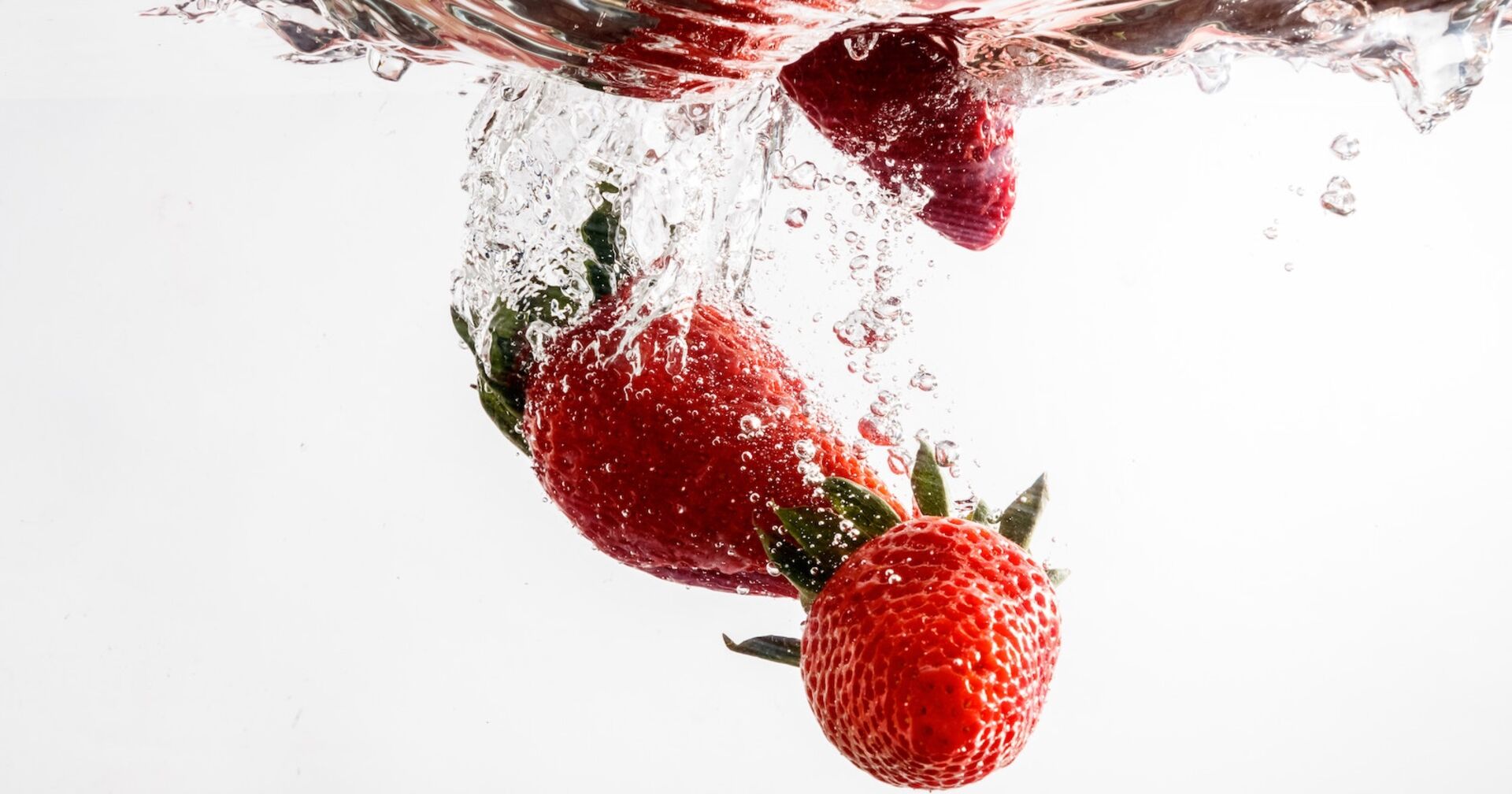 Erdbeeren fallen in Wasser und sprudeln