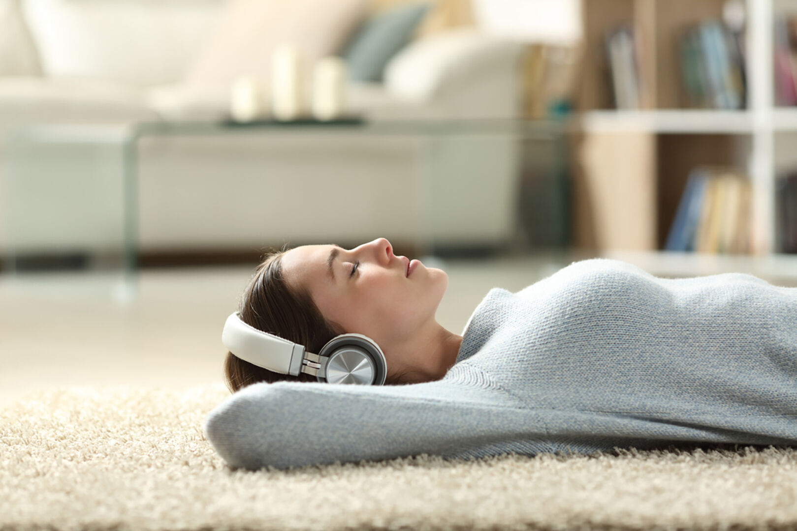 Frau liegt am Boden und hört Musik | Credit: iStock.com/Pheelings Media