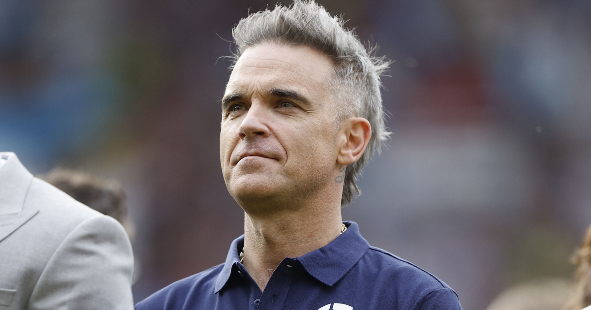 Robbie Williams mit grauen Haaren und einem Polo-Shirt in Großaufnahme