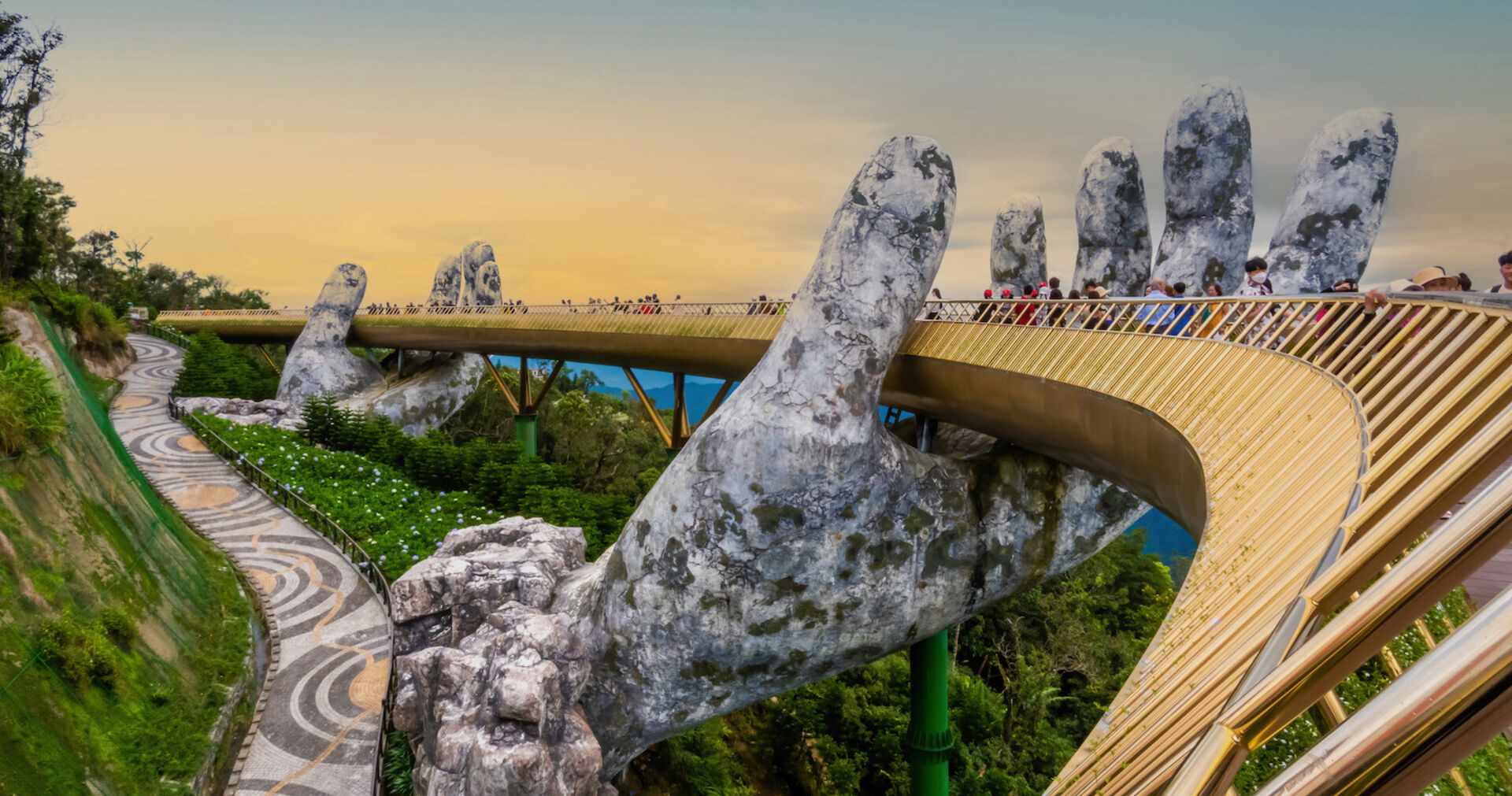 Zwei steinerne Hände tragen eine goldene Brücke in Vietnam