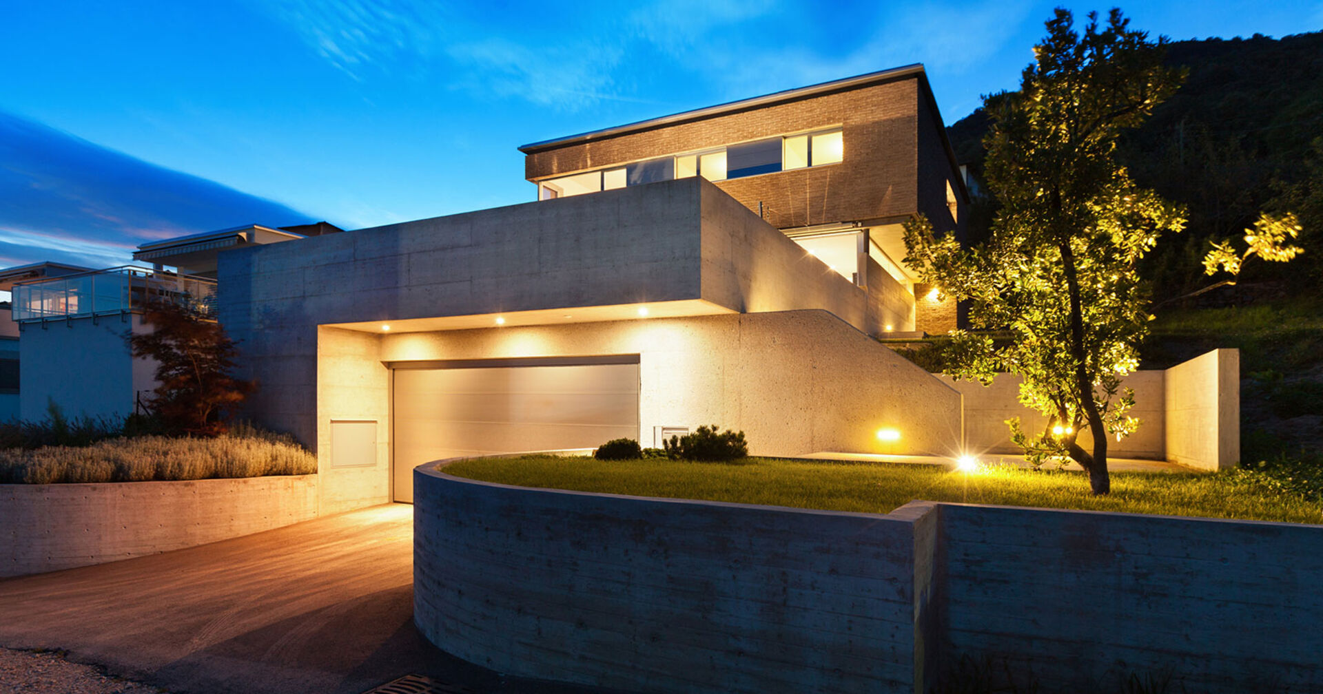 Beleuchtetes modernes Wohnhaus in der Abenddämmerung | Credit: iStock.com/piovesempre