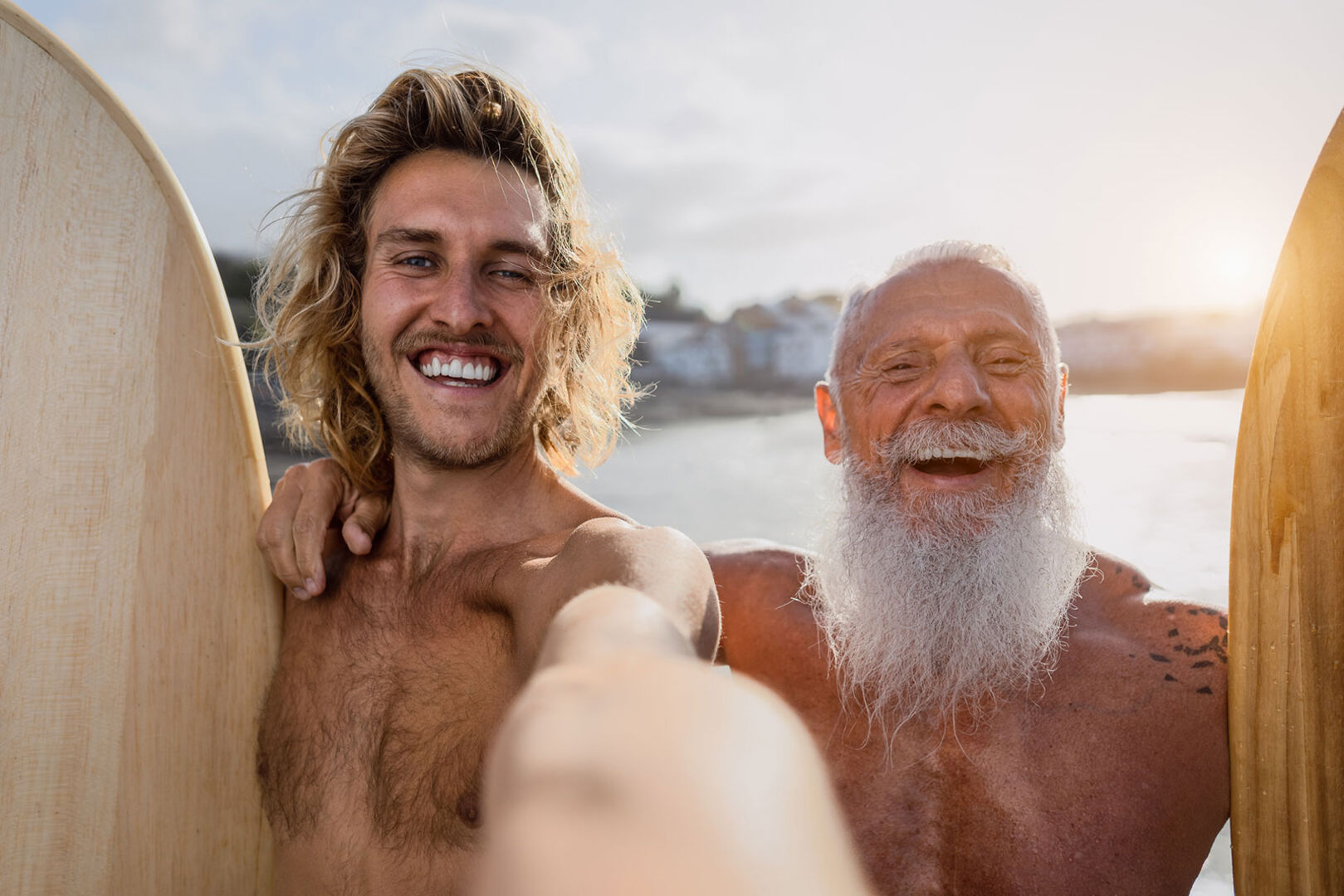Junger Mann und alter Mann mit Surfbrettern am Strand | Credit: iStock.com/Alessandro Biascioli
