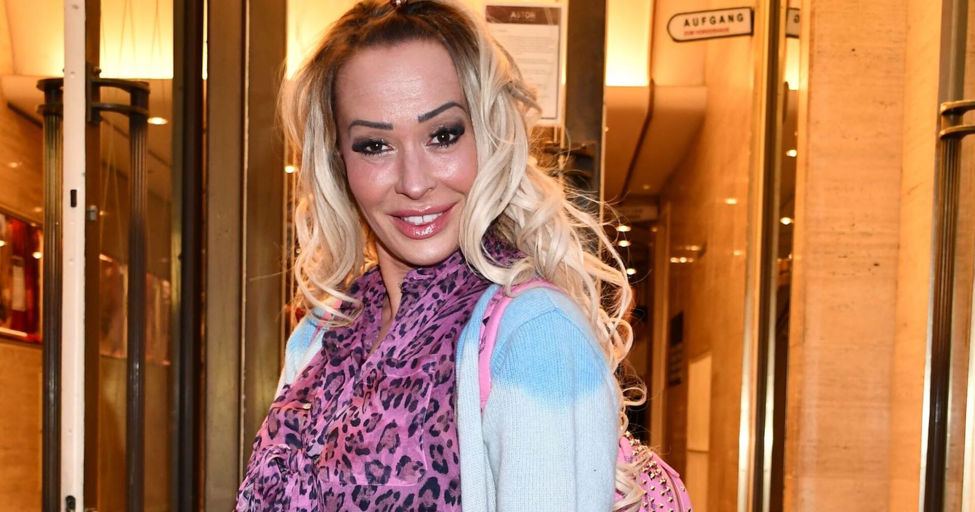 Eine Frau mit blondierten Haaren und einer Leoparden Print Bluse.