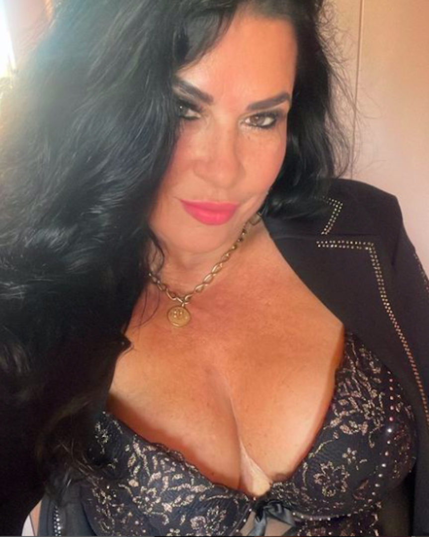 Eine Frau mit tiefem Ausschnitt schaut in die Kamera.