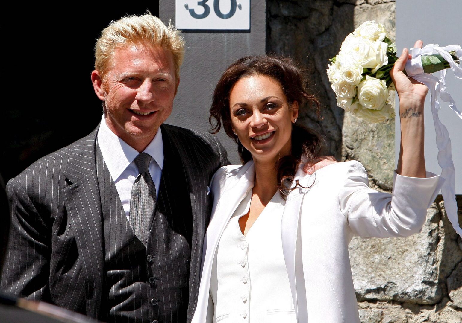 Ein Mann und eine Frau nach der Hochzeit. Sie hat einen Brautstrauß in der Hand.