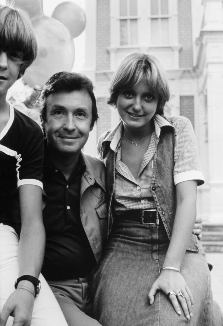 Ein schwarz-weiß Foto mit einem Mann und zwei Kindern im Teenager-Alter.