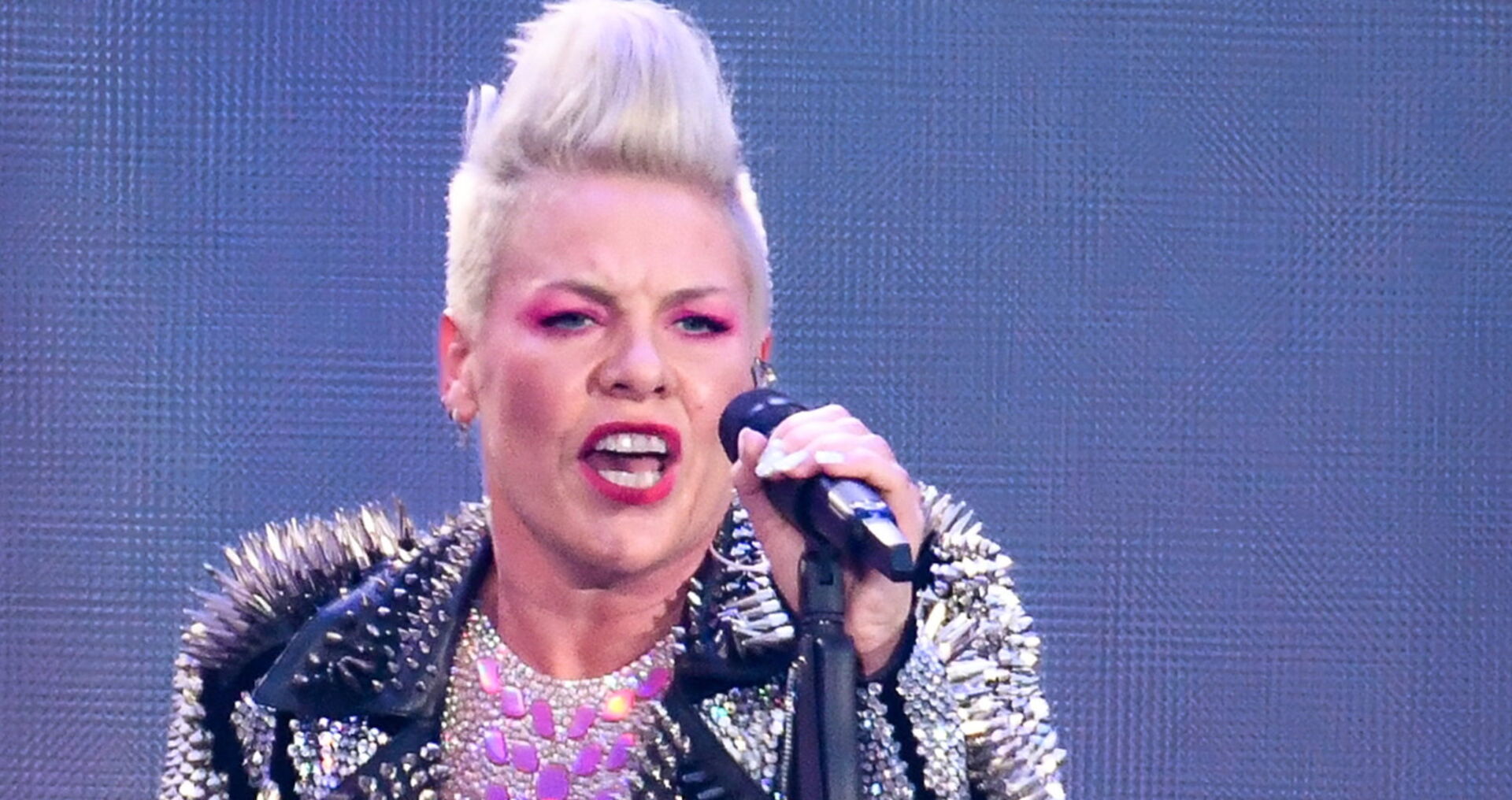 Eine Frau mit platinblonden Haaren singt in ein Mikrophon.