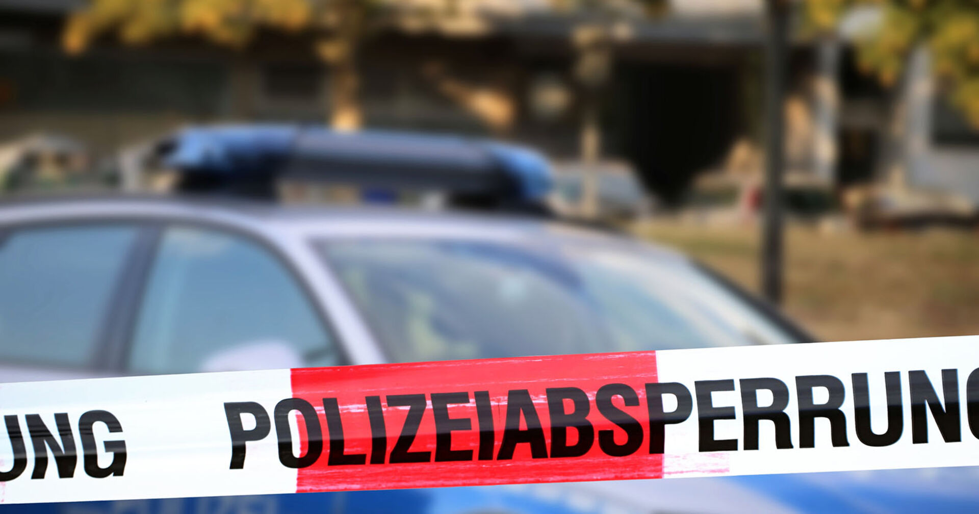 Polizeiabsperrung mit Polizeiauto im Hintergrund