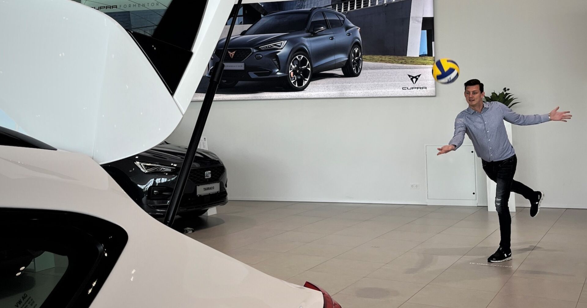 Mann wirft Volleyball in den Kofferraum eines Autos | Credit: Porsche Wien