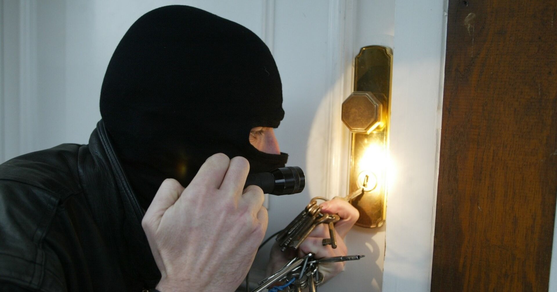 Ein Einbrecher bricht eine Türe auf.