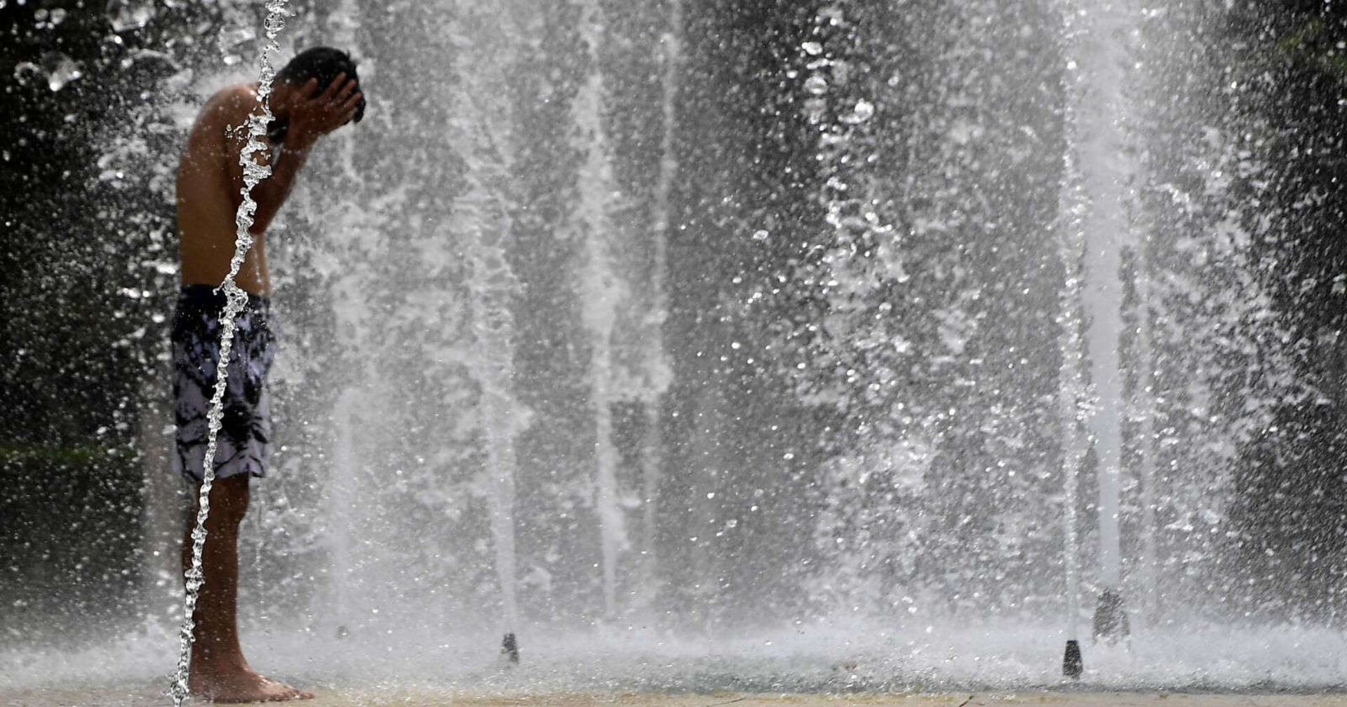 Bub kühlt sich in einem Brunnen ab.