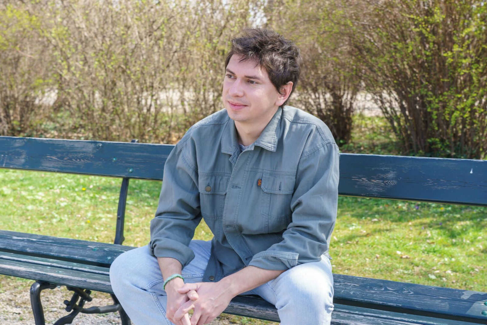 Julian le Play sitzt nachdenklich auf einer Parkbank.