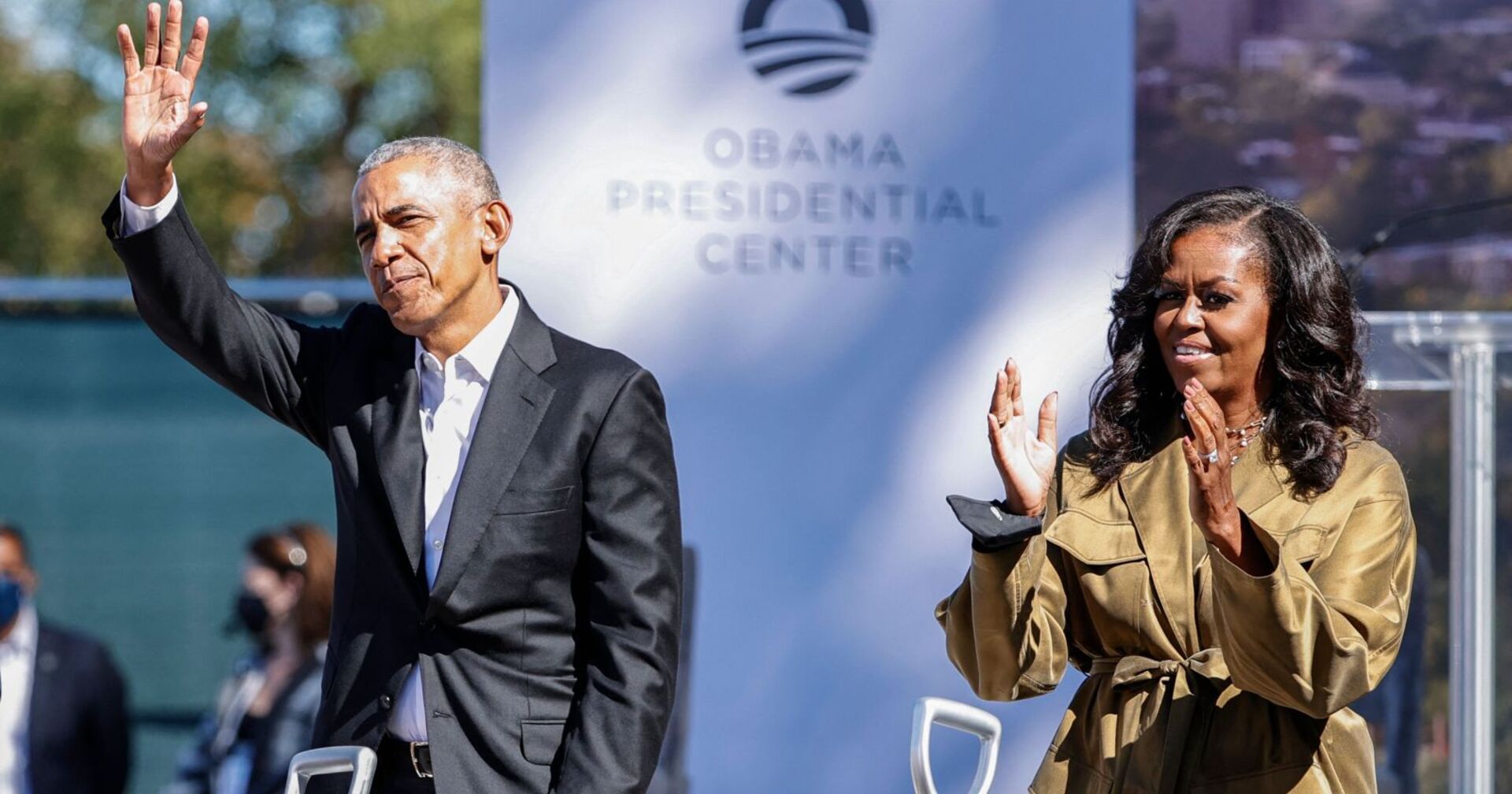 Barack und Michelle Obama klatschen und winken bei einer Veranstaltung.