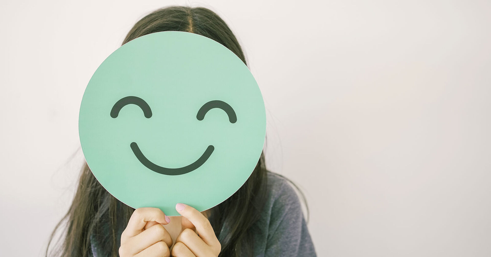 Mädchen mit einem Smiley vor dem Gesicht | Credit: iStock.com/SewcreamStudio