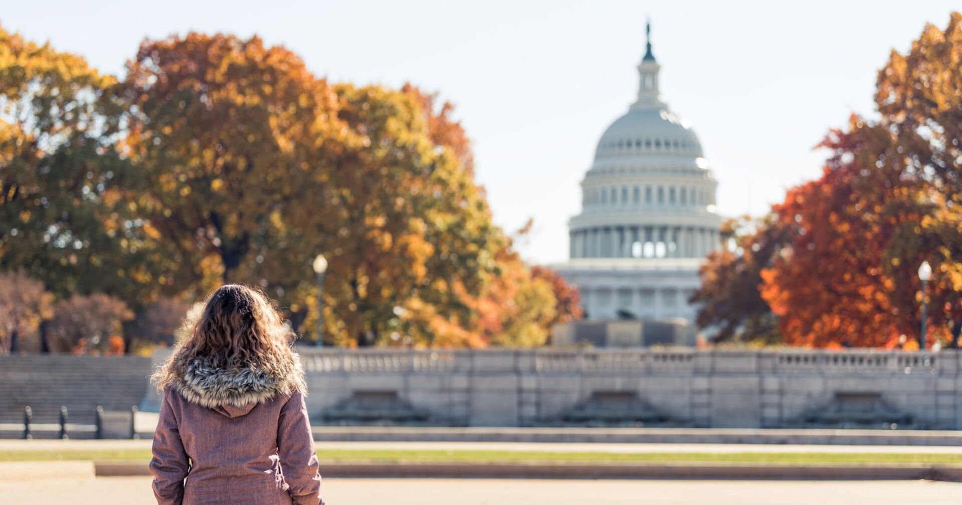 Junge Frau sitzt auf einer Bank in Amerika | Credit: iStock.com/ablokhin