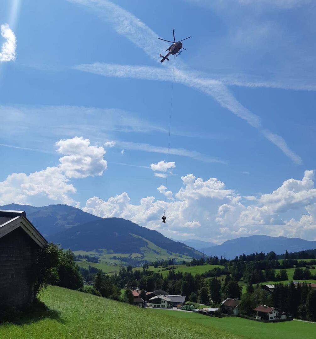 Bergretter hängen mit einem Seil am Hubschrauber.