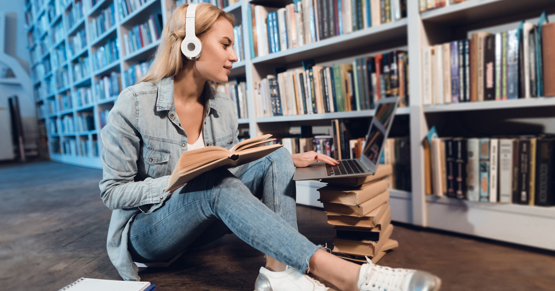 Schülerin sitzt mit Kopfhörern vor dem Laptop in der Bücherei.