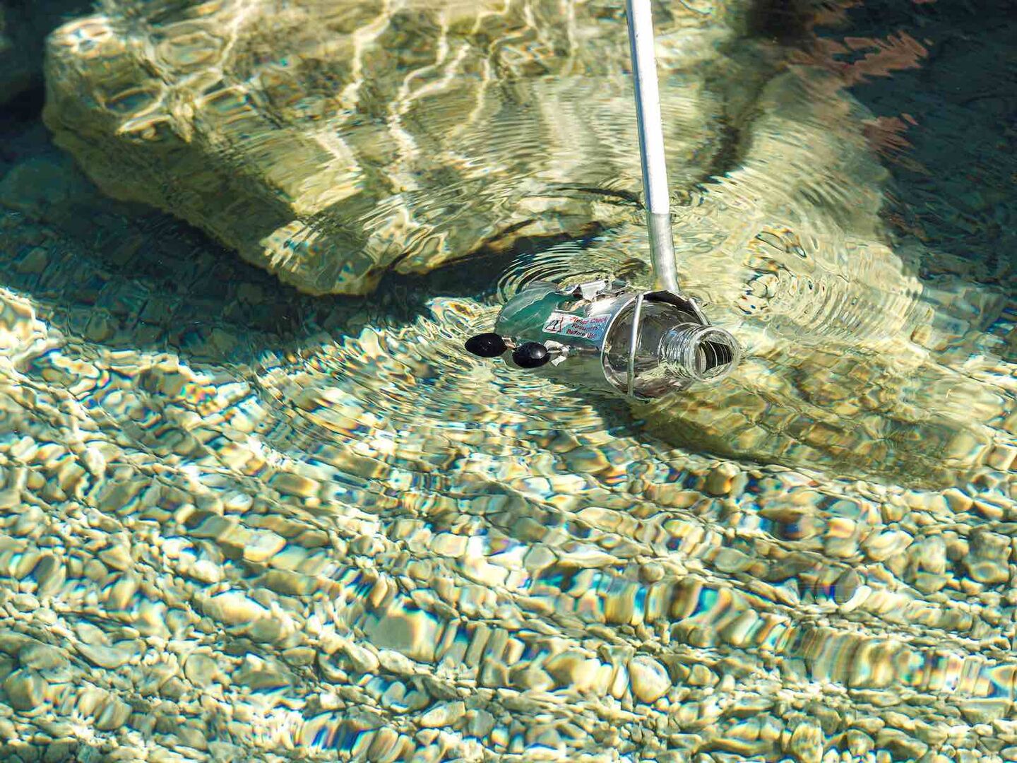 Probeentnahme im Attersee mit einer Glasflasche.