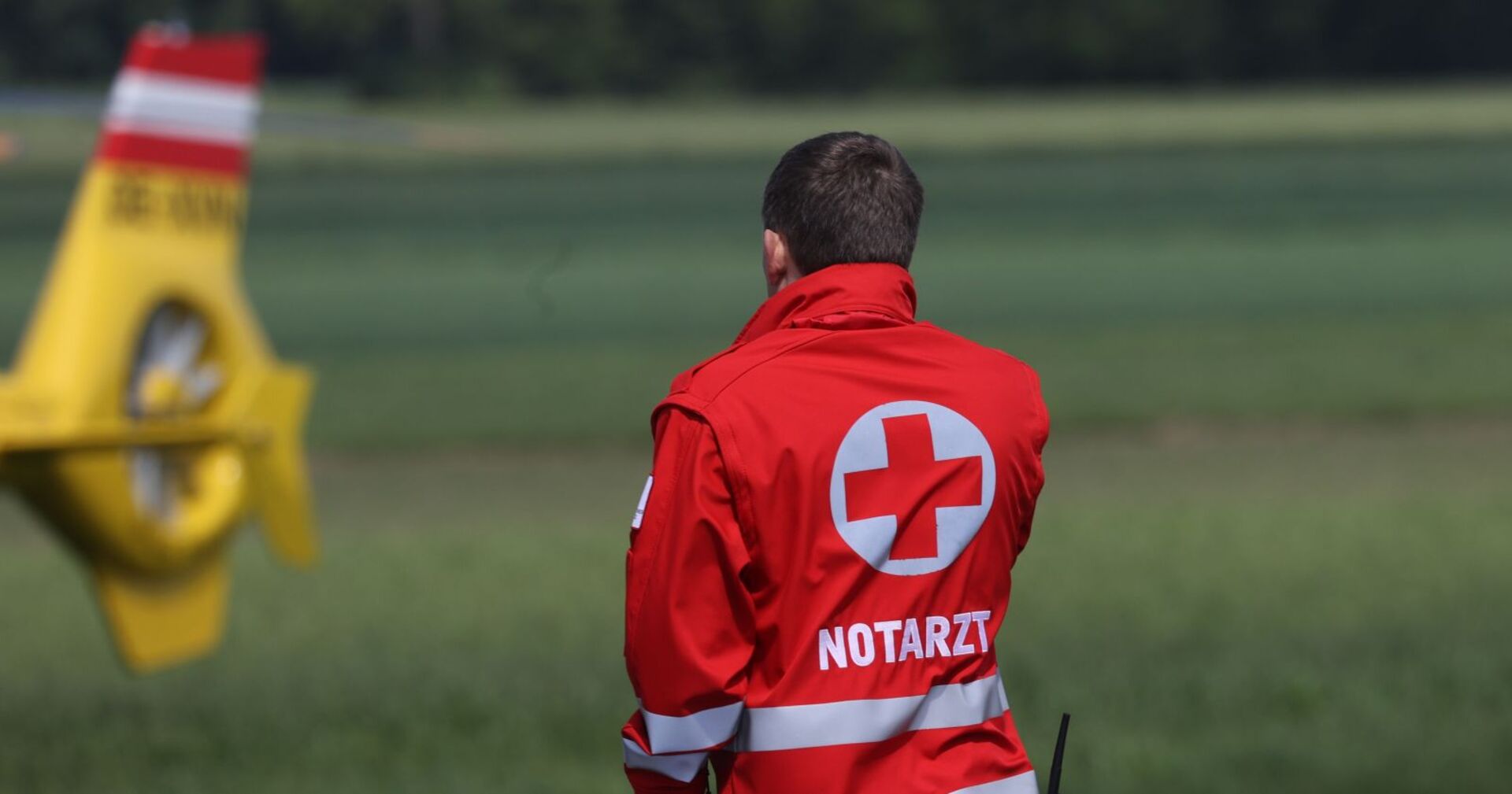 Einen Notarzt, im Hintergrund ein Hubschrauber.