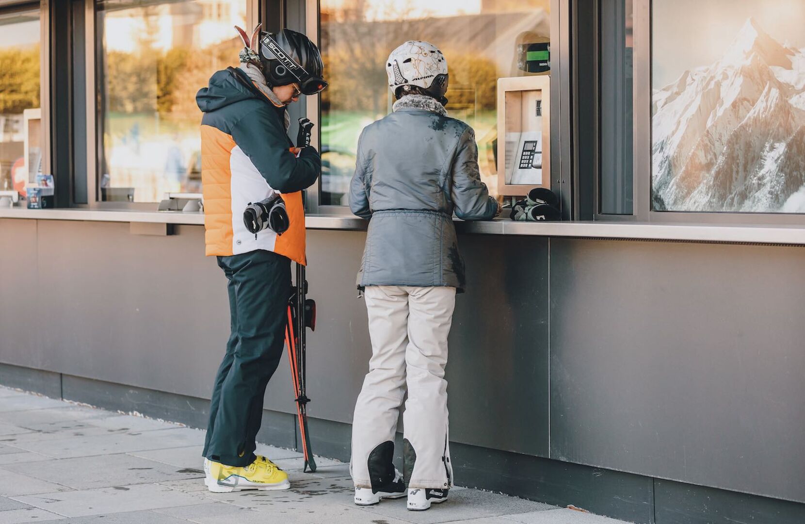 Zwei Skifahrer kaufen an der Kasse ein Skiticket.