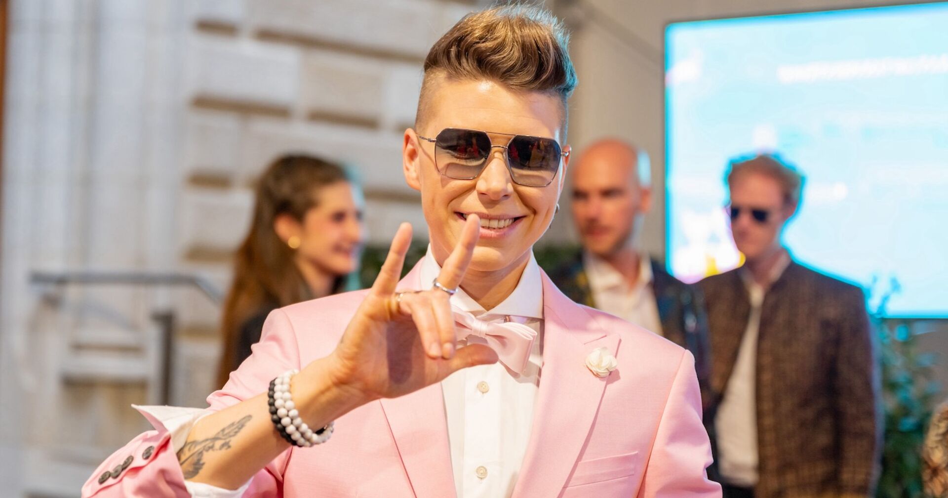 Virginia Ernst mit Sonnenbrille und in reinem rosaroten Anzug.