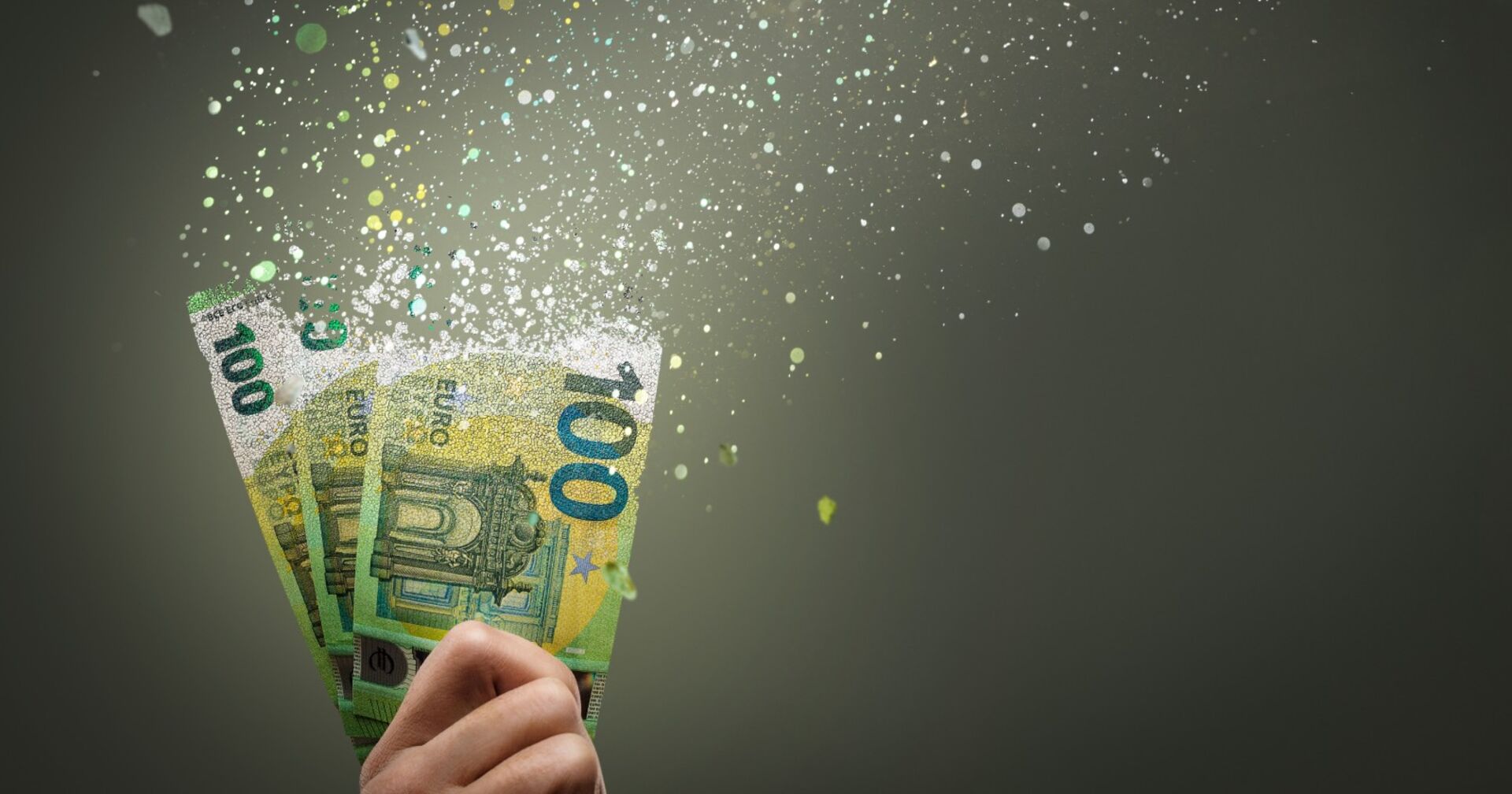 Drei 100 Euro-Scheine, die sich in einer Hand in Luft aufzulösen beginnen