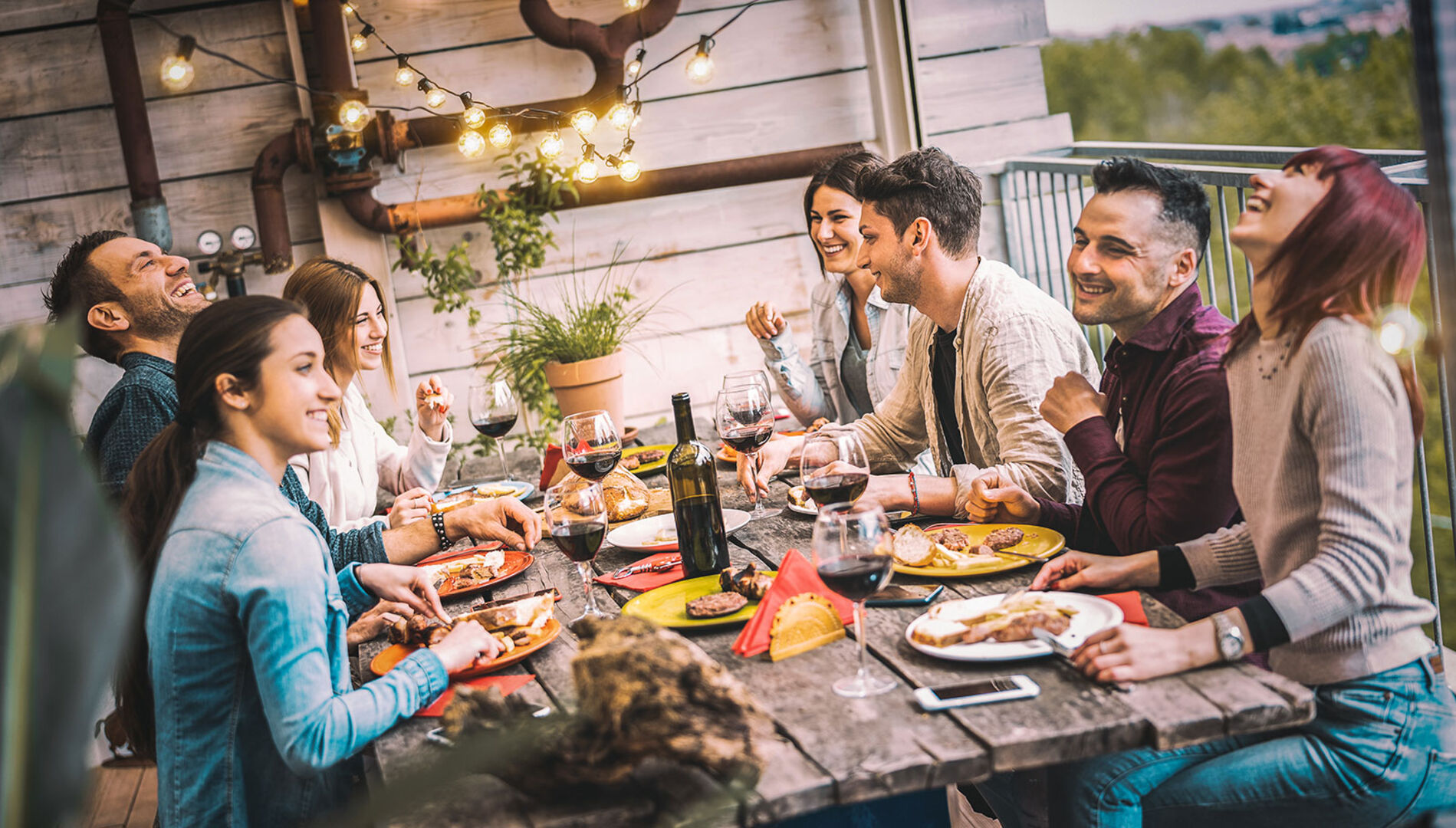 Junge Frauen und Männer beim gemeinsamen Essen auf der Terrasse | Credit: iStock.com/ViewApart