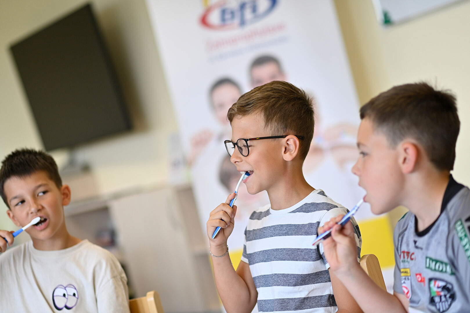 Drei junge Schüler putzen sich die Zähne
